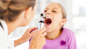 a young girl is getting her throat inspected by a doctor at a checkup